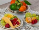 Fotografia kulinarna przedstawia ciasto owocowe języczek z truskawkami i malinami. W tle pomarańcze i winogrona
